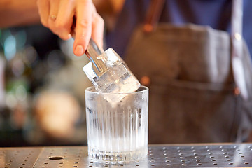 Image showing bartender adding ice cube into glass at bar