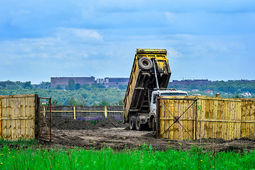 Image showing The dumper brought and dumps earth in the open warehouse