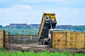 Image showing The dumper brought and dumps earth in the open warehouse