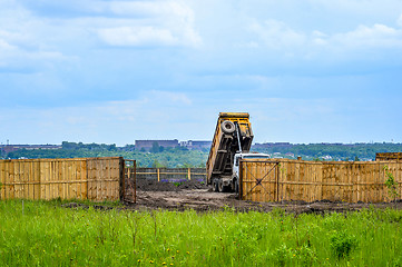 Image showing The dumper brought and dumps earth in the open warehouse