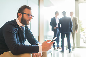 Image showing Businessman using smart phone while sitting in waiting room.