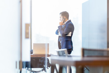 Image showing Businessman talking on a mobile phone while looking through window.