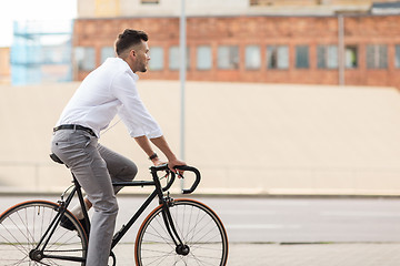 Image showing man with headphones riding bicycle on city street