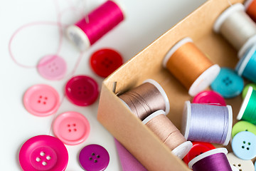 Image showing box with thread spools and sewing buttons on table