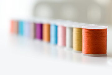 Image showing row of colorful thread spools on table