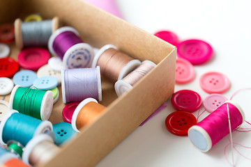 Image showing box with thread spools and sewing buttons on table