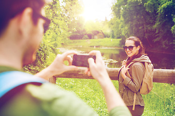 Image showing couple with backpacks taking picture by smartphone