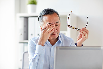 Image showing tired businessman with glasses at laptop in office