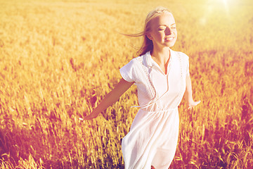 Image showing smiling young woman in white dress on cereal field