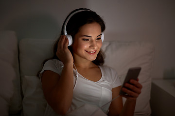 Image showing woman with smartphone and headphones in bed