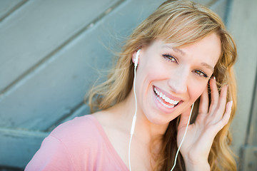 Image showing Outdoor Portrait of Young Adult Brown Eyed Woman Listening To Mu