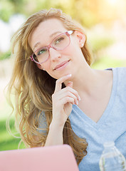 Image showing Young Adult Woman Wearing Glasses Outdoors Using Her Laptop.