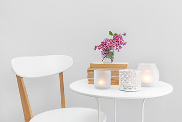 Image showing Candle lights, books and flowers on a white table