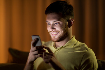 Image showing happy young man with smartphone at night