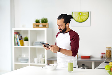 Image showing man with tablet pc eating breakfast at home