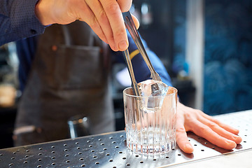 Image showing bartender adding ice cube into glass at bar