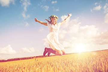 Image showing happy woman in wreath jumping on cereal field