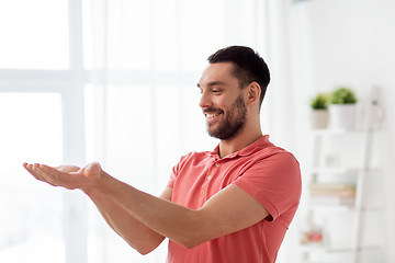 Image showing happy man holding something imaginary at home