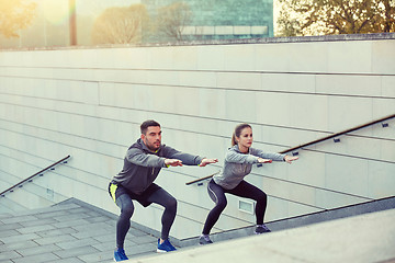 Image showing couple doing squats on city street stairs