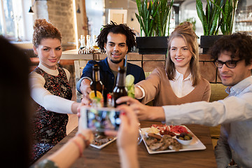 Image showing happy friends clinking drinks at bar or cafe