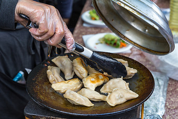 Image showing Dumplings frying on grill pan on food stall.