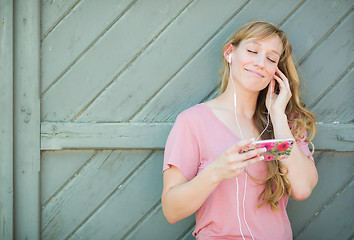 Image showing Outdoor Portrait of Young Adult Brown Eyed Woman Listening To Mu