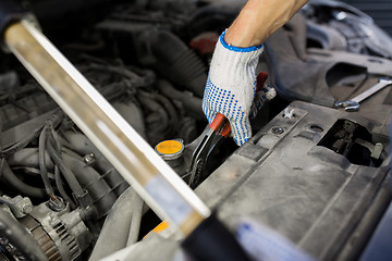 Image showing mechanic man with pliers repairing car at workshop