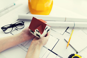 Image showing close up of hands with house model above blueprint