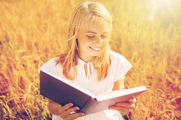 Image showing smiling young woman reading book on cereal field