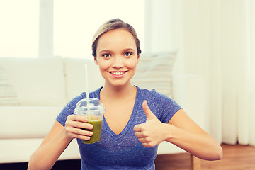 Image showing happy woman with cup of smoothie showing thumbs up