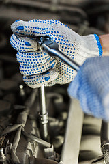 Image showing mechanic man with wrench repairing car at workshop