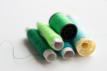 Image showing green and blue thread spools on table