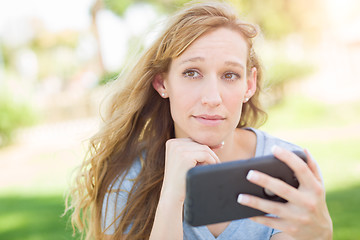 Image showing Concerned Young Woman Outdoors Looking At Her Smart Phone.