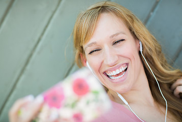 Image showing Young Adult Woman Wearing Earphones Taking a Selfie with Her Sma