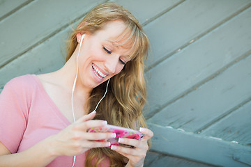 Image showing Outdoor Portrait of Young Adult Brown Eyed Woman Listening To Mu