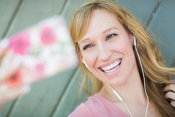 Image showing Young Adult Woman Wearing Earphones Taking a Selfie with Her Sma