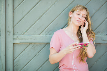 Image showing Outdoor Portrait of Young Adult Brown Eyed Woman Listening To Mu