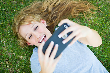 Image showing Young Adult Woman Laying in Grass Taking a Selfie with Her Smart