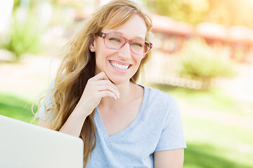 Image showing Young Adult Woman Wearing Glasses Outdoors Using Her Laptop.