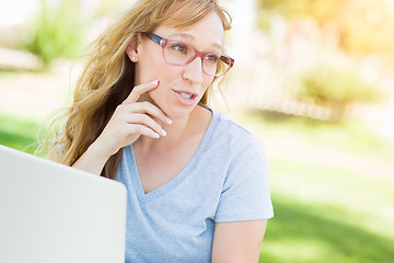 Image showing Young Adult Woman Wearing Glasses Outdoors Using Her Laptop.