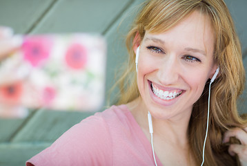 Image showing Young Adult Woman Wearing Earphones Taking a Selfie with Her Sma