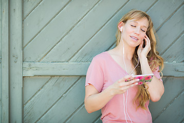Image showing Outdoor Portrait of Young Adult Brown Eyed Woman Listening To Mu