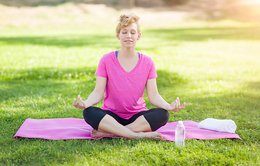 Image showing Young Fit Adult Woman Outdoors on The Grass Doing the Yoga Lotus