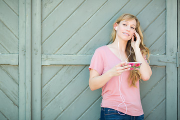 Image showing Outdoor Portrait of Young Adult Brown Eyed Woman Listening To Mu