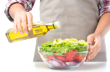 Image showing Cook is pouring olive oil into salad