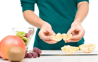 Image showing Cook is peeling orange for fruit dessert