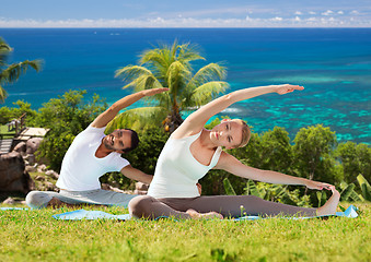 Image showing happy couple making yoga exercises outdoors