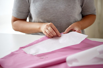 Image showing woman with pins stitching paper pattern to fabric