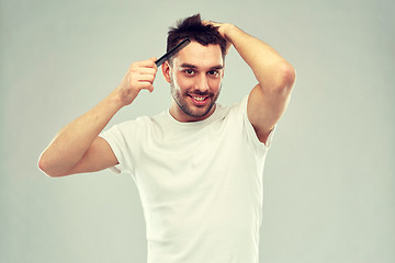 Image showing happy man brushing hair with comb over gray