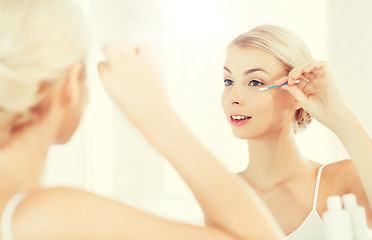 Image showing woman fixing makeup with cotton swab at bathroom